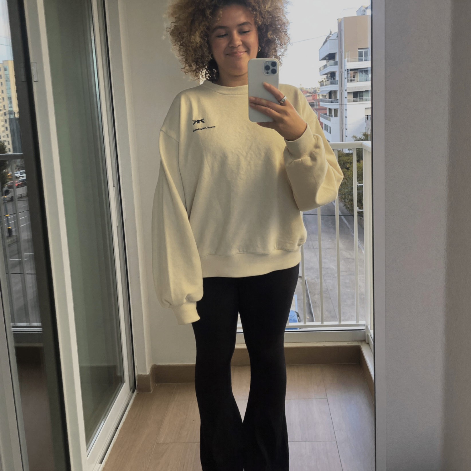 Cliente usando a calça Noir preta em foto frontal com moletom claro, mostrando caimento real no corpo.